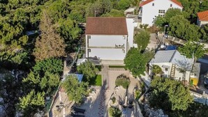 A residential area with a white building, a paved driveway, and a view of the sea. - Two bedroom apartment with garden (Trpanj)