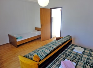 A room with two beds, one with a plaid bedspread and the other with a plain white sheet. - Two bedroom apartment (B) (Murter)