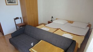 Ein Zimmer mit einem Bett, einem Sofa, einem Sessel und einem Nachttisch mit einer Lampe.
