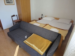 Ein Zimmer mit einem Bett, einem Sofa, einem Sessel und einem Nachttisch mit einer Lampe.
