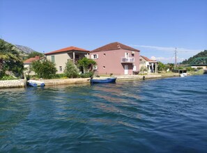 A waterfront property with a canal, two boats, and buildings with balconies. - Two Bedroom Apartment with Balcony and River View (Rogotin)