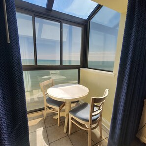 A balcony with a glass table and chairs, overlooking a body of water. - Beach Life Honeymoon Suite with Jacuzzi DW1613 (Myrtle Beach)
