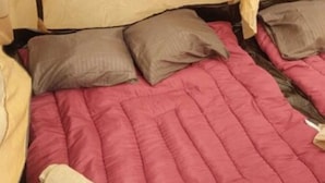 Ein Bett mit einer rosa Steppdecke, zwei Kissen und einem beigen Kopfteil.