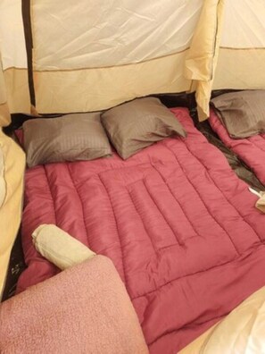 Ein Bett mit einer rosa Steppdecke, zwei Kissen und einem beigen Kopfteil.