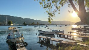 Un lago tranquilo con barcos amarrados a muelles de madera, rodeado de colinas y cielos despejados.