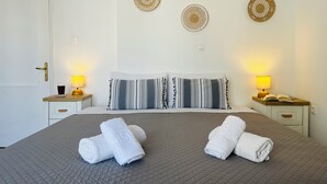 Una cama bien hecha con dos almohadas, dos lámparas de noche y dos adornos de pared.