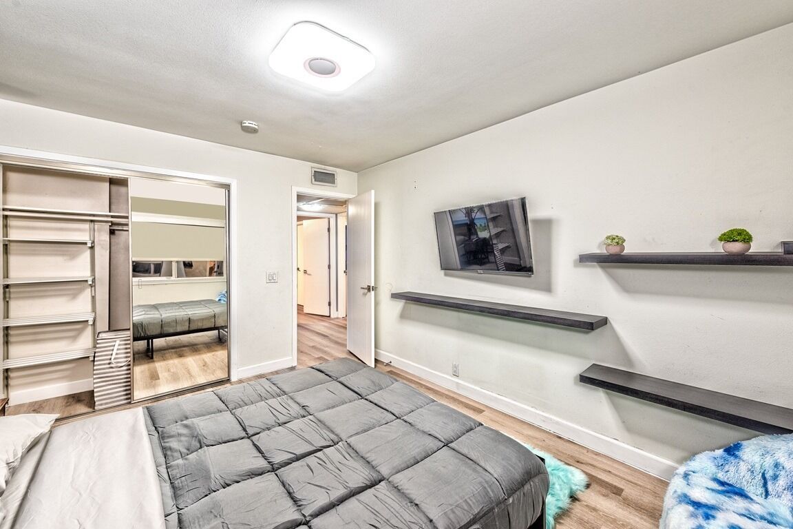 Un dormitorio moderno con una cama, un televisor montado en la pared y un vestidor.