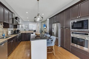 A modern kitchen with dark cabinetry, stainless steel appliances, and a central island with seating. - Bronzeville Executive Retreat (Chicago)