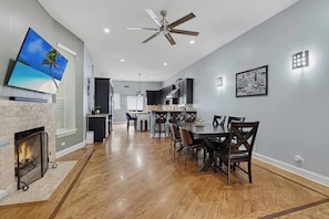 A spacious kitchen with modern appliances, a dining area with a large table and chairs, and a fireplace. - Bronzeville Executive Retreat (Chicago)