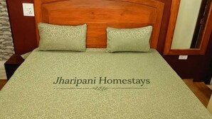A bed with a patterned bedspread and two pillows, a wooden headboard, and a wall-mounted light switch. - 2-Bedroom Self-Contained Accommodation with Entire Private Floor (Doom Gaon)