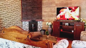 A living room with a fireplace, a television, and floral-patterned furniture. - 2-Bedroom Self-Contained Accommodation with Entire Private Floor (Doom Gaon)