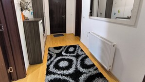 A hallway with a black and white patterned rug, a white radiator, and a mirror on the wall. - Peaceful & Cozy Apartment Gostivar (Gostivar)