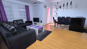 Ein modernes Wohnzimmer mit Sofa, Fernseher und Essbereich.
