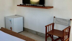 A room with a bed, a small white refrigerator, a wooden chair, a mounted television, and a shelf with a star decoration. - Casa Mangaba da Praia (Prado)