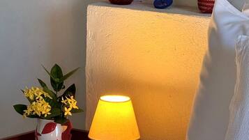 A bedside table with a lamp, a vase with flowers, and a decorative item on a nightstand.