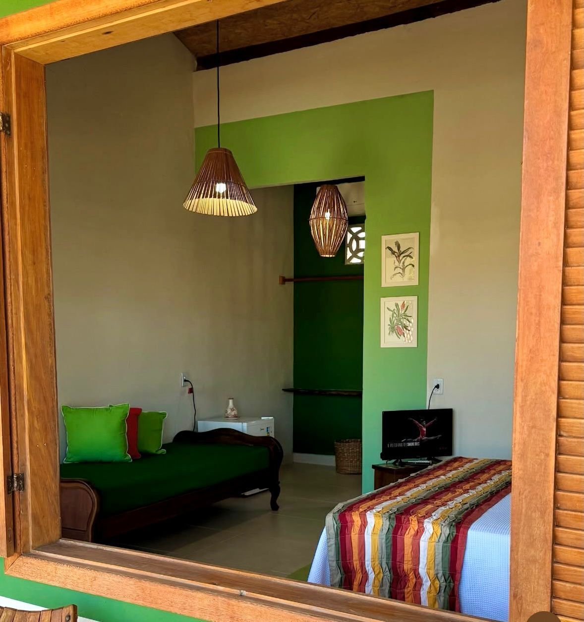 Une chambre avec un lit, une télévision et un mur vert.