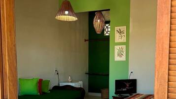 Une chambre avec un lit, une télévision et un mur vert.