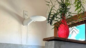 A bathroom with a shower, a red vase, and a window with a view. - Casa Mangaba da Praia (Prado)