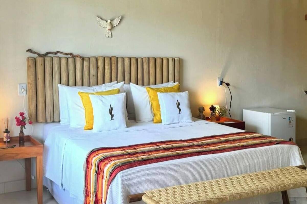 A bed with a striped blanket, a wooden headboard, and a wall-mounted bird decoration.