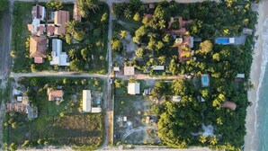 An aerial view of a coastal property with multiple buildings, a beach, and dense vegetation. - Casa Mangaba da Praia (Prado)