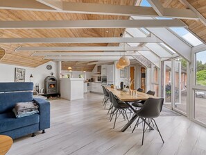 A modern kitchen with a central island, a dining area with a long table and chairs, and a cozy seating area with a sofa. - "Janne" -  from the sea by Interhome (Ringkøbing)