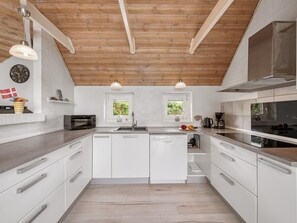 A modern kitchen with white cabinetry, a wooden ceiling, and pendant lighting. - "Janne" -  from the sea by Interhome (Ringkøbing)
