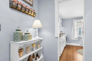 A hallway with a white shelf holding decorative items, a white lamp, and a wall clock.