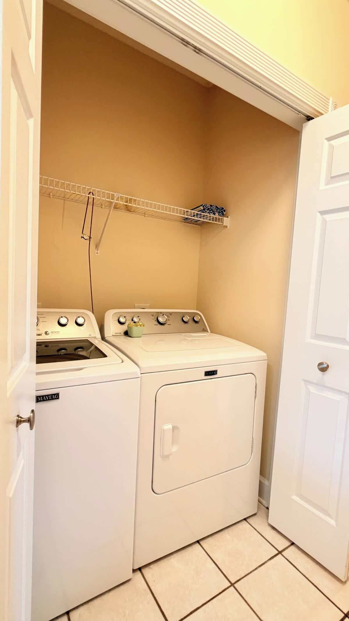Une buanderie équipée d’un lave-linge et d’un sèche-linge, d’un étendoir et d’une petite étagère.
