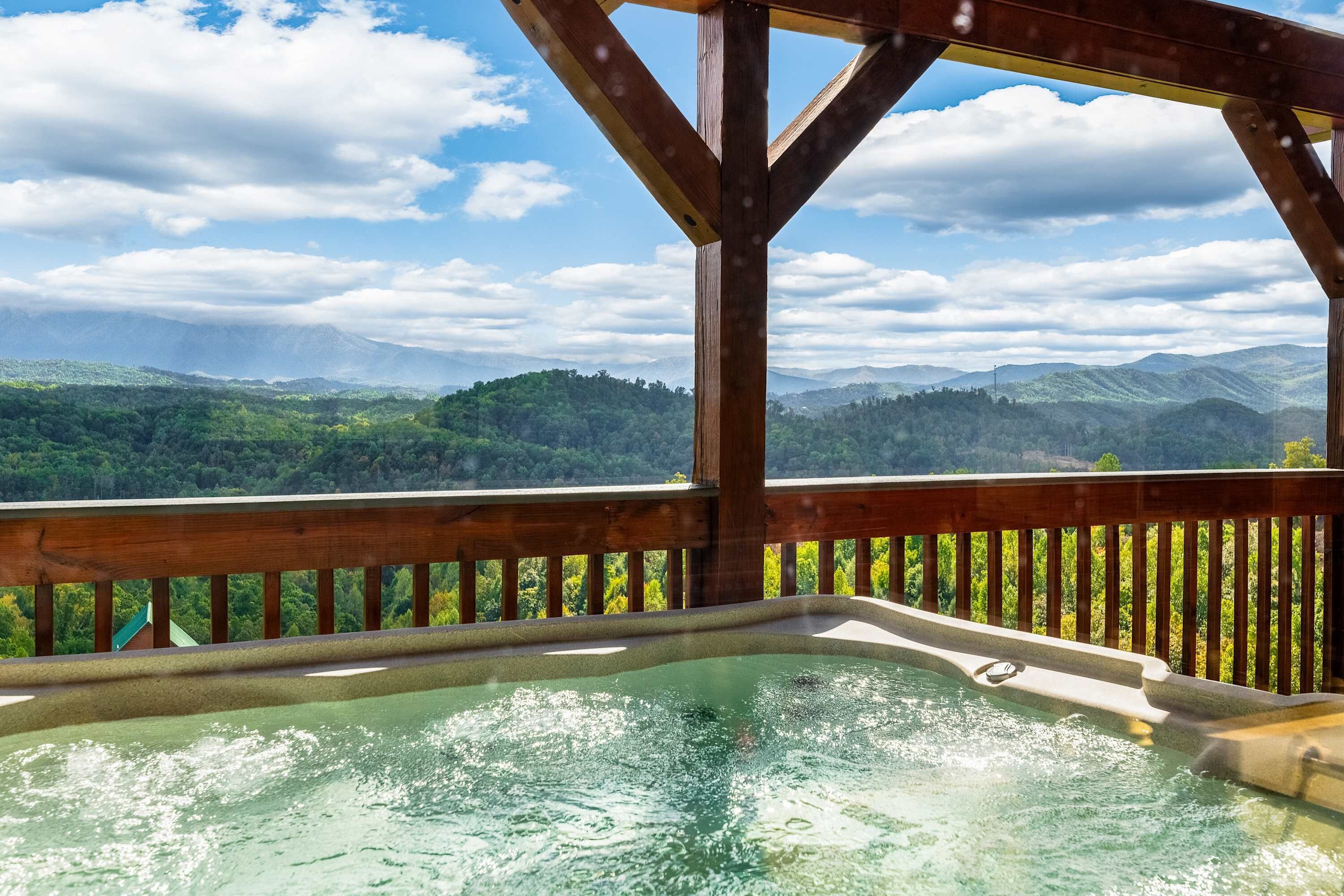 Una vasca idromassaggio con un rivestimento in legno e vista sulle montagne verdi.