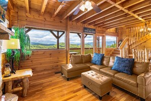 Ein Holzhaus-Interieur mit Holzboden, Ledersofa und Bergblick.