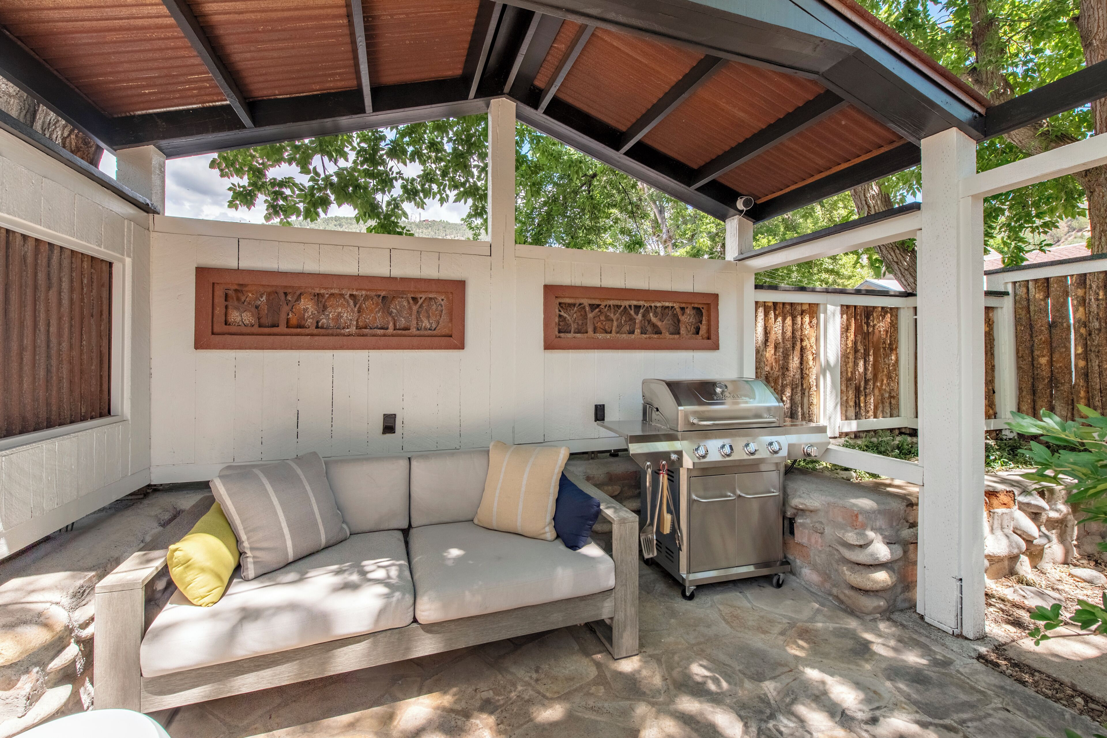 Une terrasse extérieure dotée d’un barbecue intégré et d’un espace salon confortable avec des coussins.
