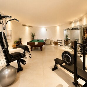 Ein Fitnessraum mit Trainingsgeräten, einem Billardtisch und einem Poolbillardtisch.