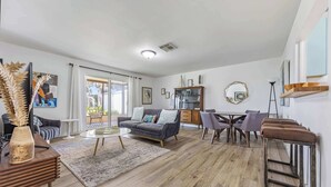 Ein modernes Wohnzimmer mit Sofa, Couchtisch und Essbereich mit Stühlen.