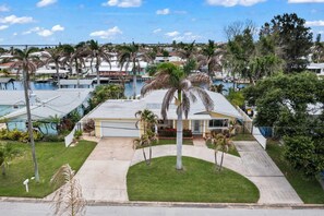 Un quartier résidentiel avec une maison, une piscine et des palmiers.