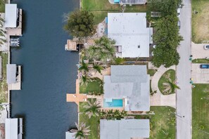 An aerial view of a residential area with a swimming pool, docked boats, and a road. - 3BR Waterfront Home with Pool & Kayaks (Cocoa Beach)