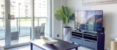 Una sala de estar moderna con un televisor de pantalla plana, una mesa de centro, una planta en maceta y un sofá.