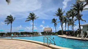 Une piscine entourée de palmiers, avec des chaises longues et des parasols.