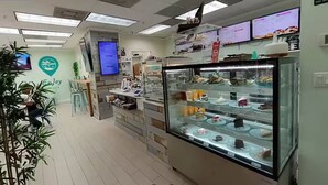 Une boulangerie avec une vitrine remplie de gâteaux et de pâtisseries, un panneau affichant le menu et une enseigne sur laquelle on peut lire : « Bon appétit ».