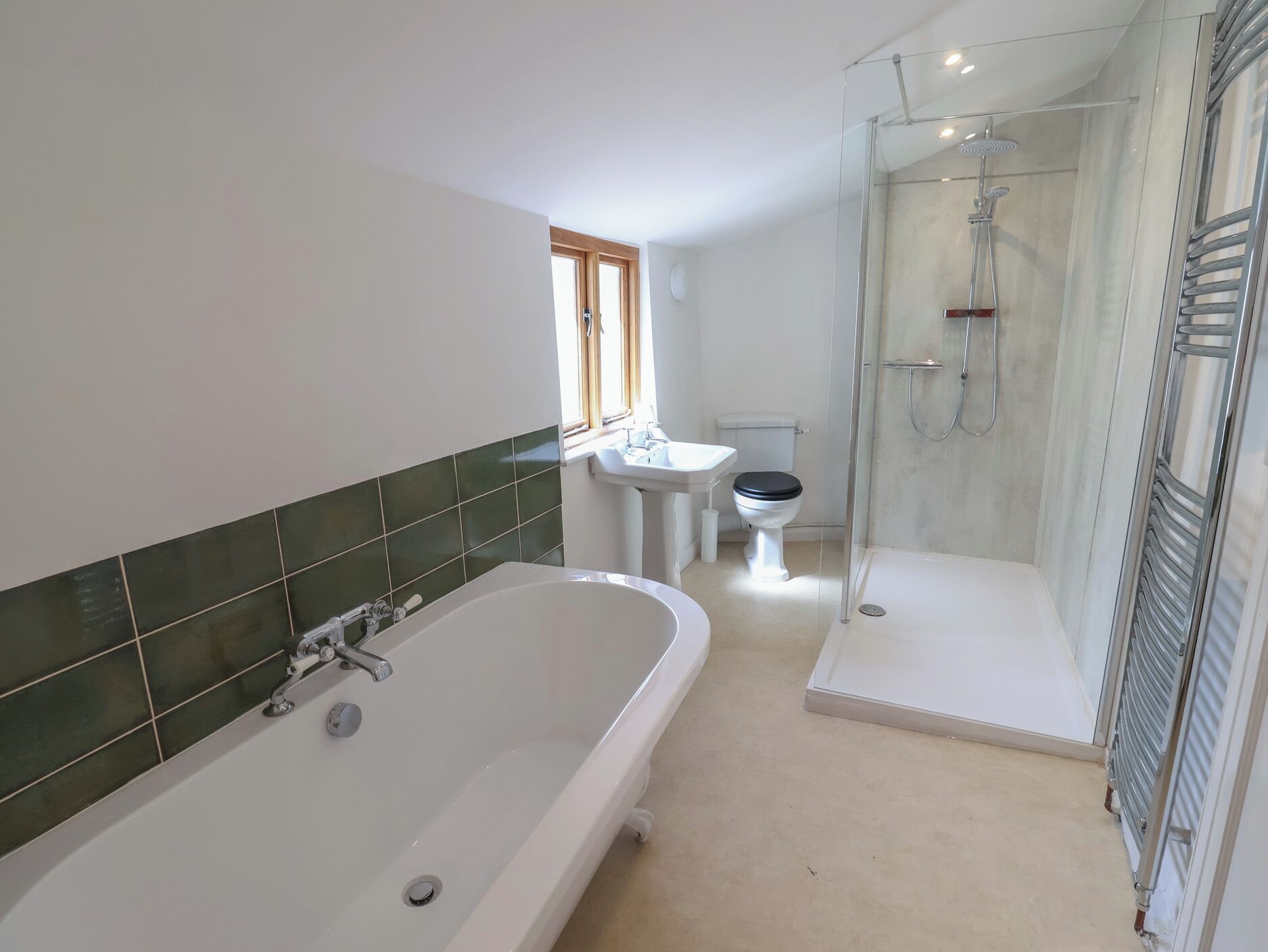 A bathroom with a bathtub, toilet, and glass-enclosed shower.