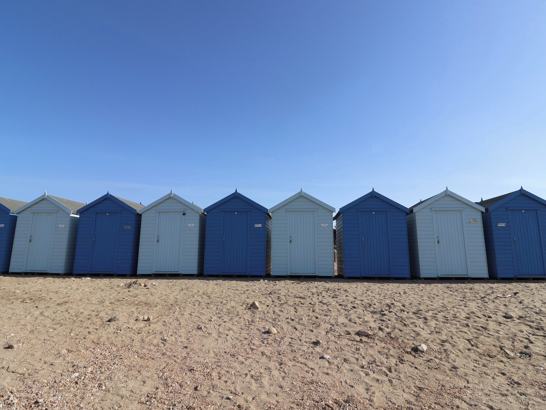 Une rangée de cabanes de plage, avec une plage de sable au premier plan.