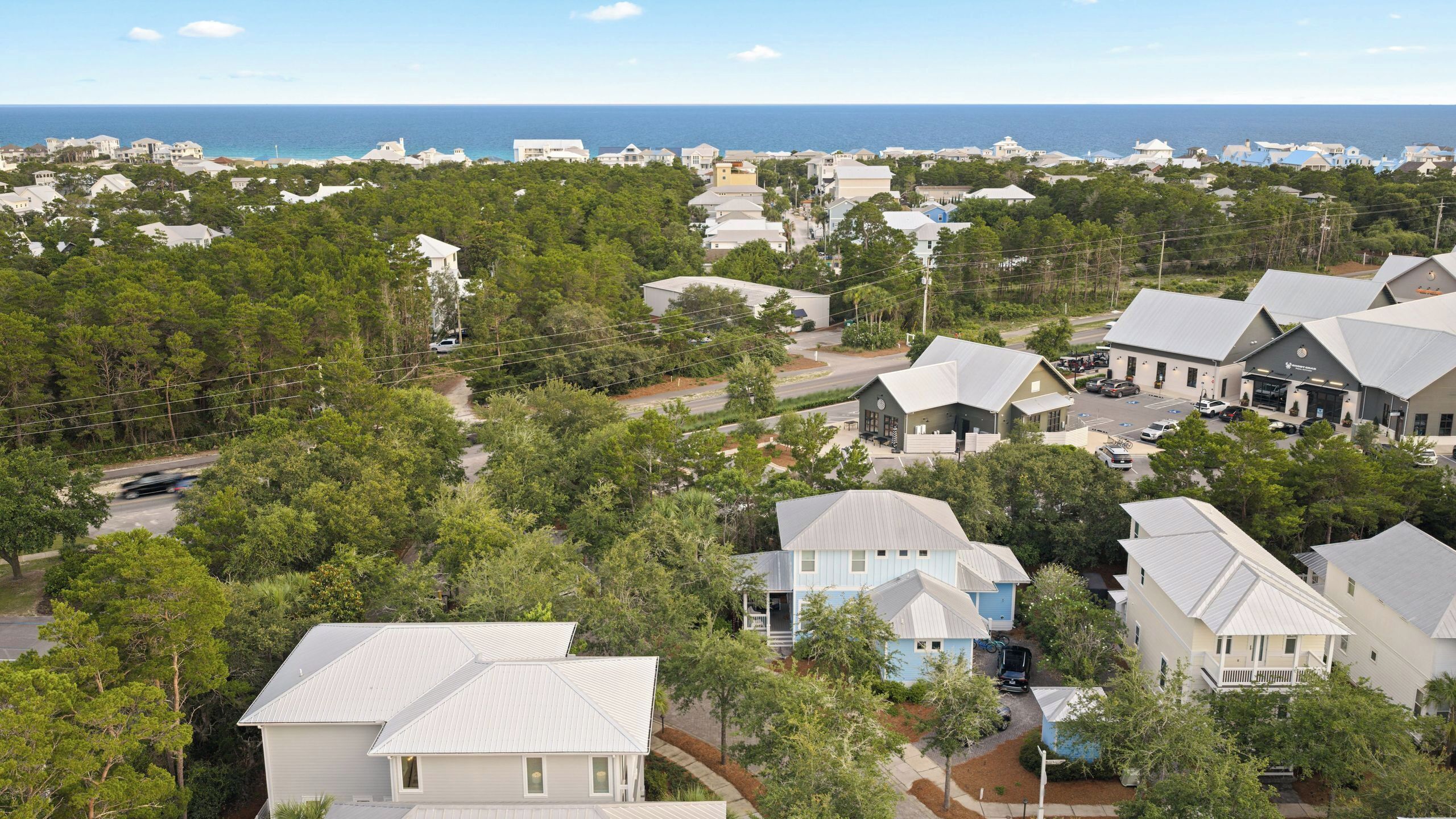 Ett bostadsområde vid kusten med hus, en väg och utsikt över havet.