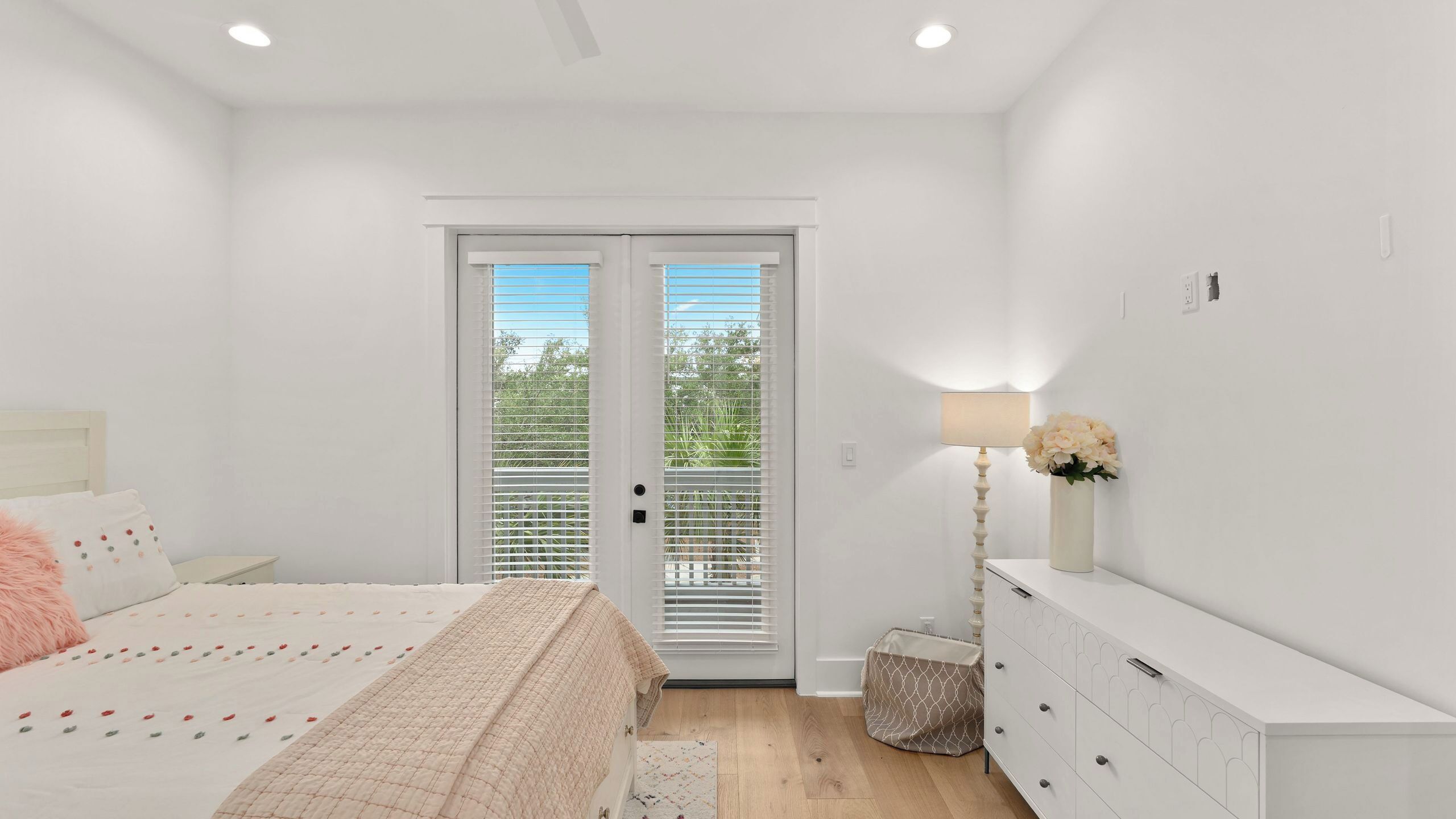 Un dormitorio con cama, cómoda, lámpara y vistas por la puerta.