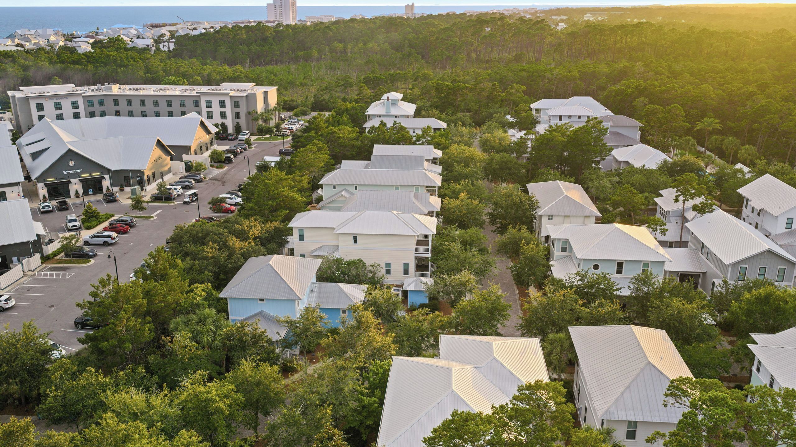 A residential area with houses, a parking lot, and a large building with multiple floors.