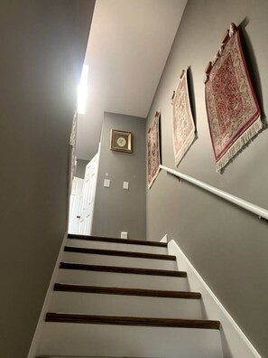 Eine Treppe mit Handlauf, grauen Wänden und gemusterten Teppichen.