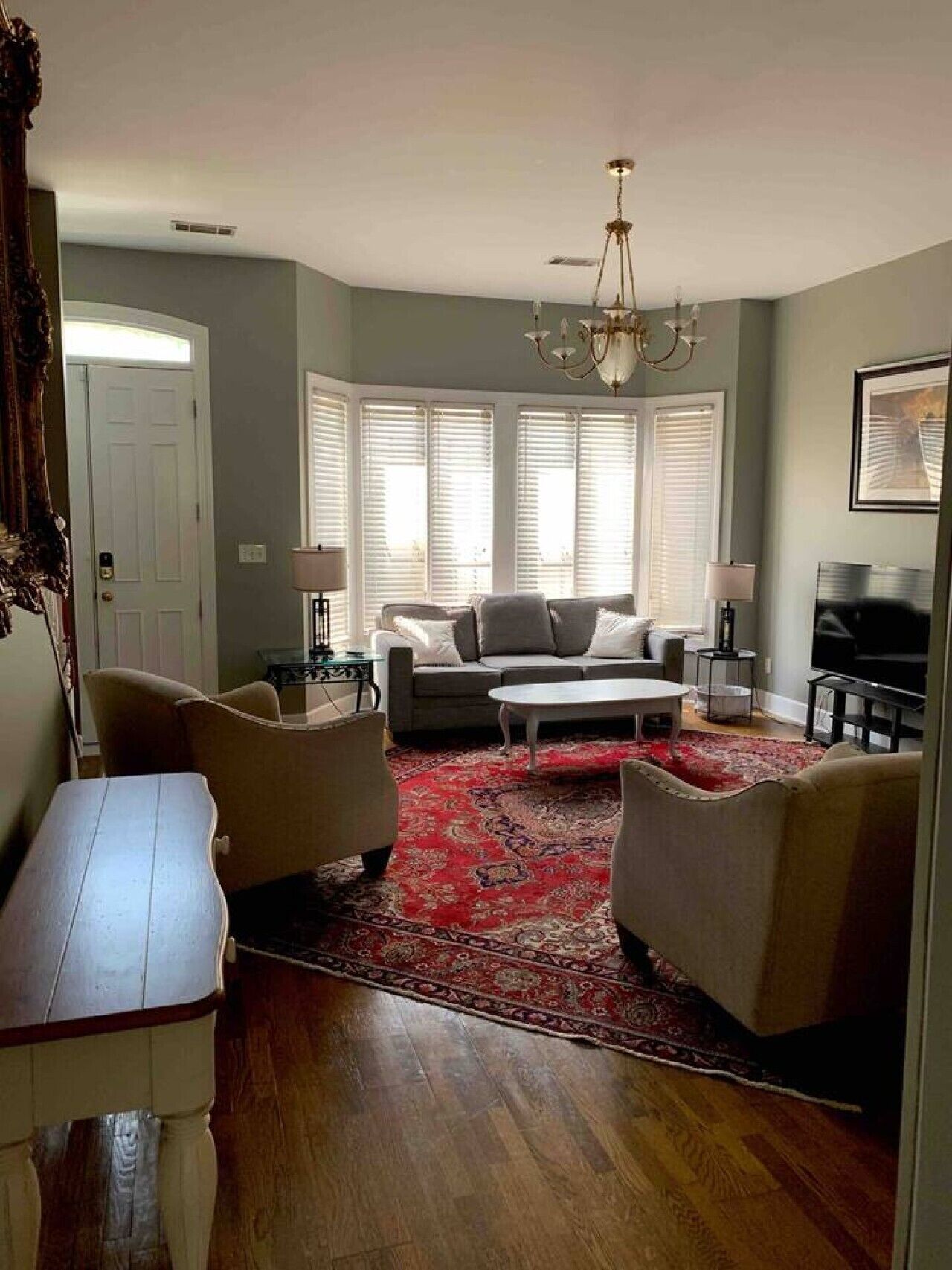 A living room with a sofa, chairs, a coffee table, a TV, and a chandelier.