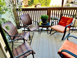 Eine Terrasse mit Korbstühlen, einem kleinen Tisch mit einer Pflanze und einem roten Sessel.