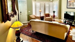 A living room with a sofa, armchairs, a chandelier, a television, and a door. - Forsyth Silk-n-art (elegance-comfort-free parking) (Savannah)