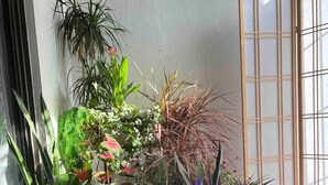 Et hjørne af et rum med forskellige potteplanter, en traditionel japansk shoji-skærm og et rundt bord.