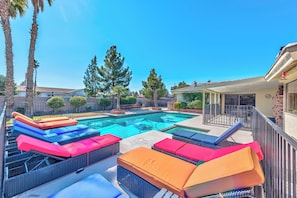 Ein Pool mit Liegestühlen und einer überdachten Terrasse.