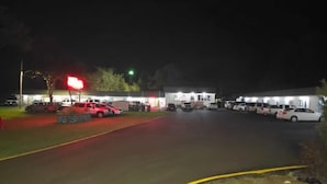 A parking lot with several cars and a building with multiple windows. - Hilltop Motel (Montello)
